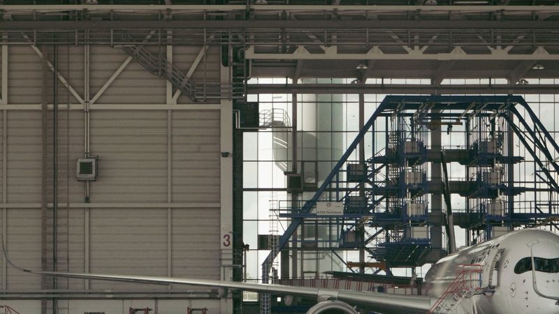 Commercial aircraft undergoing maintenance inside an industrial hangar