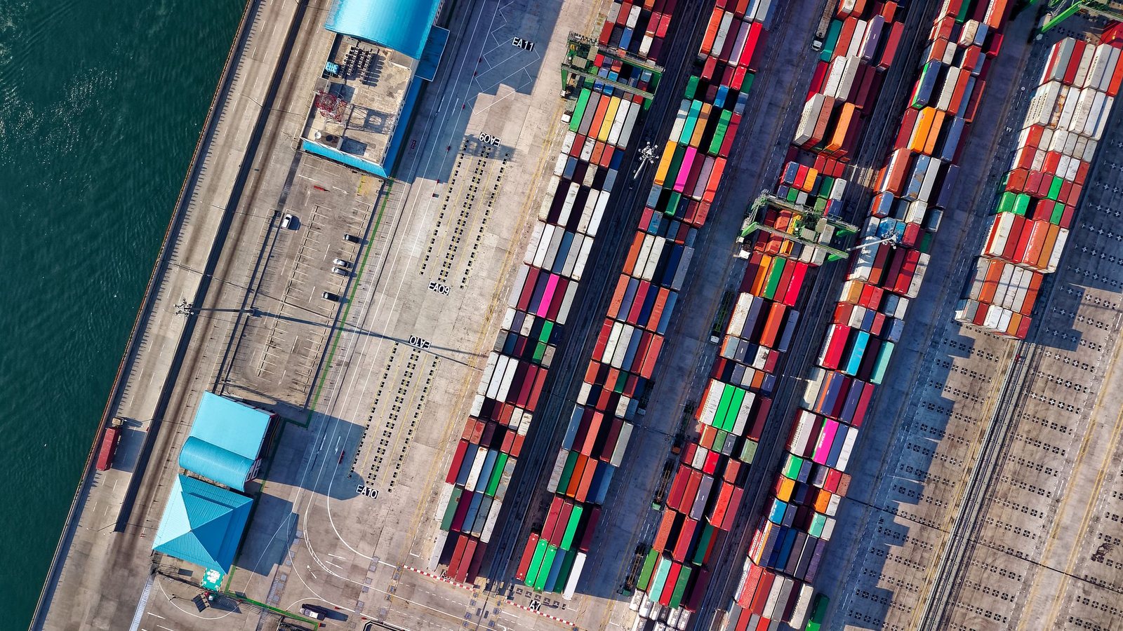 Aerial view of shipping containers stacked in rows at a port terminal