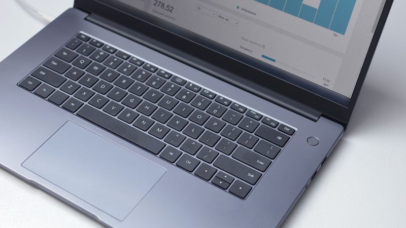 A laptop on a white desk showing a performance dashboard with bar charts