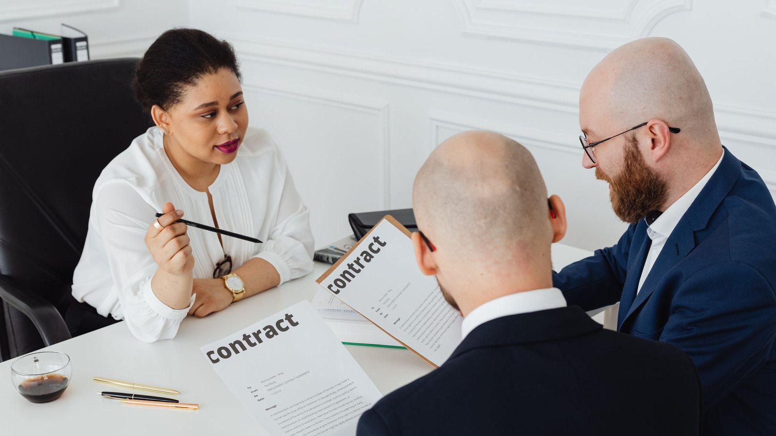 Three people reviewing contract documents together across a meeting table