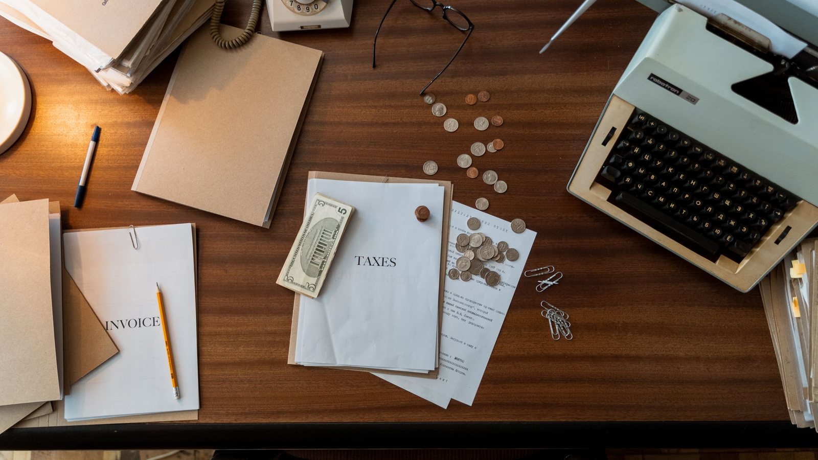 Desk flat lay with an invoice, banknotes, loose coins and a typewriter