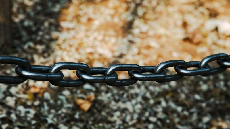Close-up of a heavy black metal chain, each link carrying the load