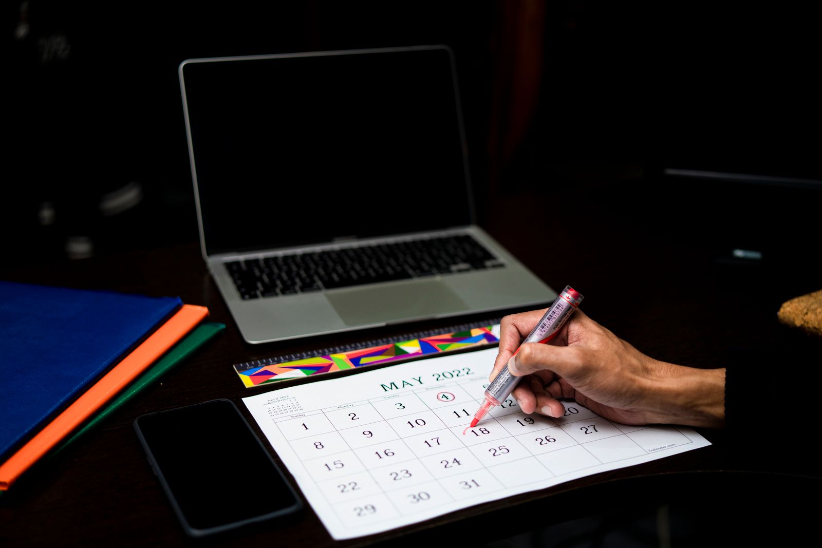 A software renewal notice date being marked on a calendar beside a laptop